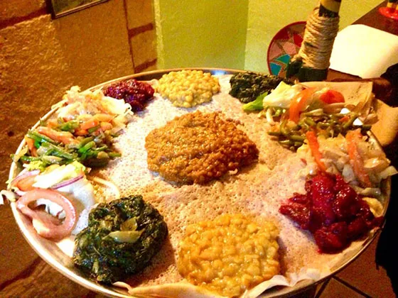 Plateau végétarien, lentilles, légumes et purées d'épices disposés sur l'injera