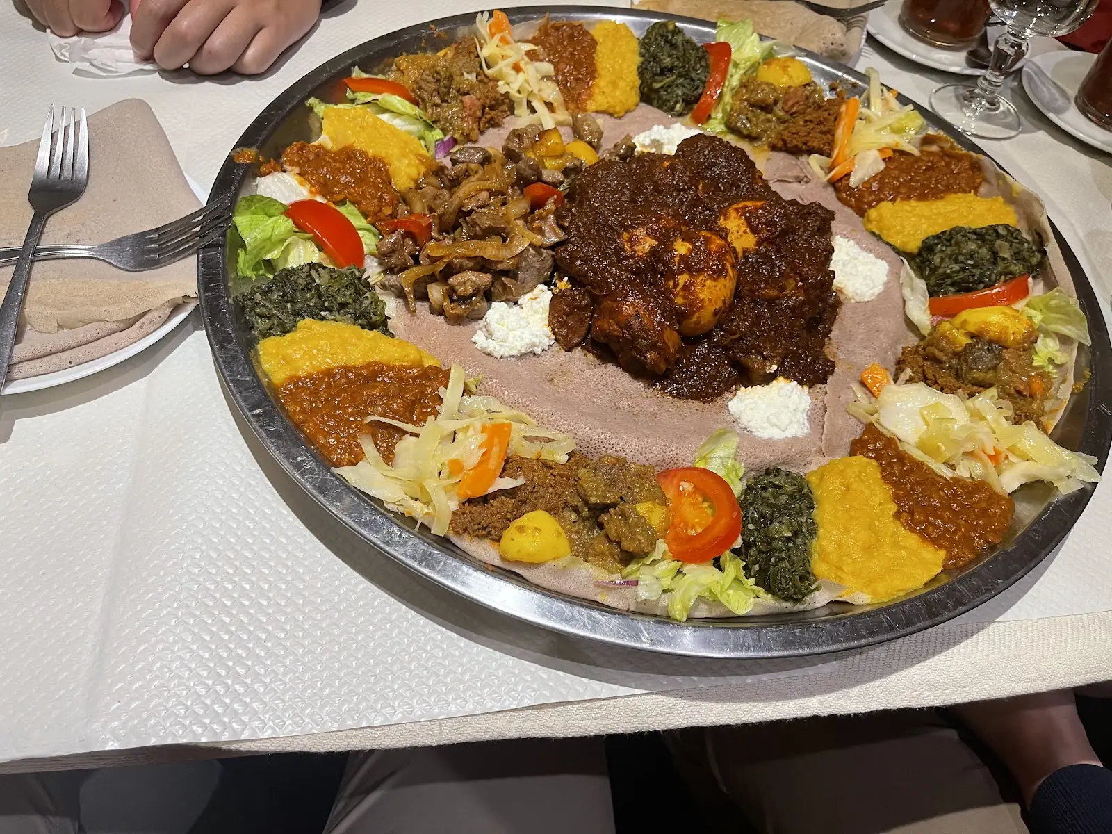 Grand plateau d'injera garni de ragoûts éthiopiens, servi au centre de la table